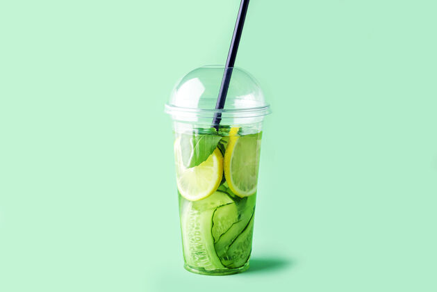 维生素新鲜清凉排毒饮料黄瓜 柠檬和罗勒在塑料杯上绿色健身罗勒鸡尾酒