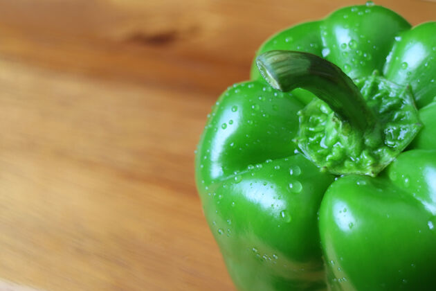 辣椒绿色的甜椒与水滴隔离在木制背景上维生素新鲜甜椒