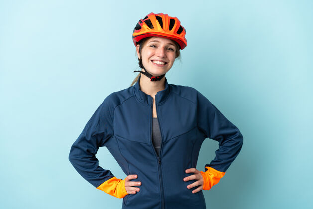 女孩在蓝色背景下 一位骑自行车的年轻女子 双臂放在臀部 面带微笑自行车手臂肖像
