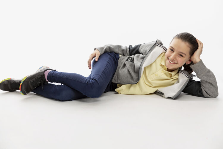 积极穿着连帽衫和牛仔裤微笑的少女躺在地板上现代欢呼年轻