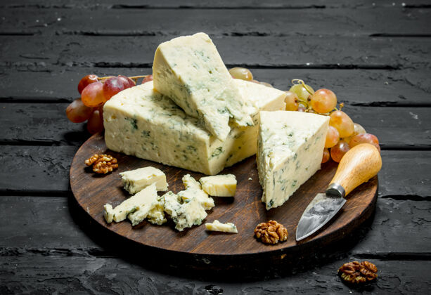 乳制品蓝色奶酪放在木板上葡萄.on黑色乡村背景开胃菜奶酪美味