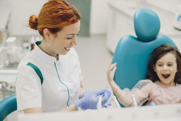 女孩年轻可爱的女性儿童口腔医生微笑着为儿童口腔科未来的牙齿手术准备器械设备牙齿帮助