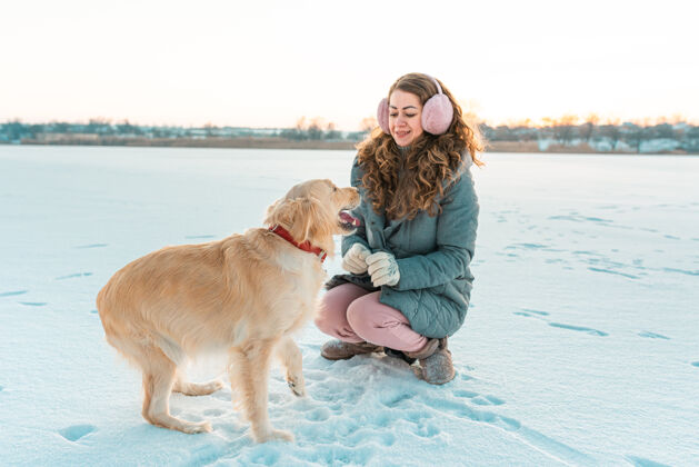 季节大金毛猎犬和女孩冬季白色景观休闲狗雪