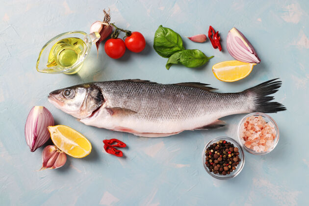 欧洲新鲜即食生鲈鱼与配料和调味品 如罗勒 柠檬 盐 胡椒 樱桃番茄和大蒜浅蓝色表面吃胡椒有机