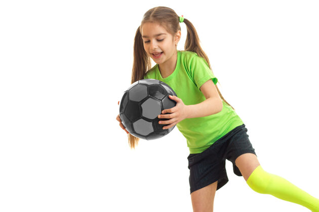 表情快乐的小女人 手里拿着五颜六色的足球 孤零零地站在白色的地板上青少年足球球