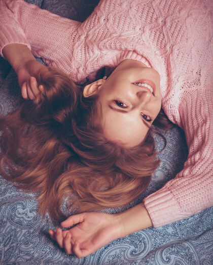 睡觉躺在床上穿着粉色毛衣 满头红发的快乐年轻女子房子头发关闭