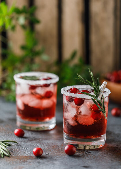 鸡尾酒红莓鸡尾酒冰圣诞节红莓饮料在玻璃装饰糖和迷迭香提神水果果汁