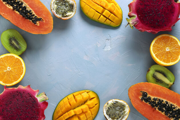 淡蓝色半幅热带水果的框架：木瓜 芒果 龙 猕猴桃 橘子和西番莲 浅蓝色表面 俯瞰 文本空间植物龙顶视图