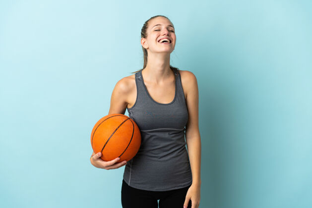 球在蓝色背景上打篮球的年轻女子笑了健身篮球肖像