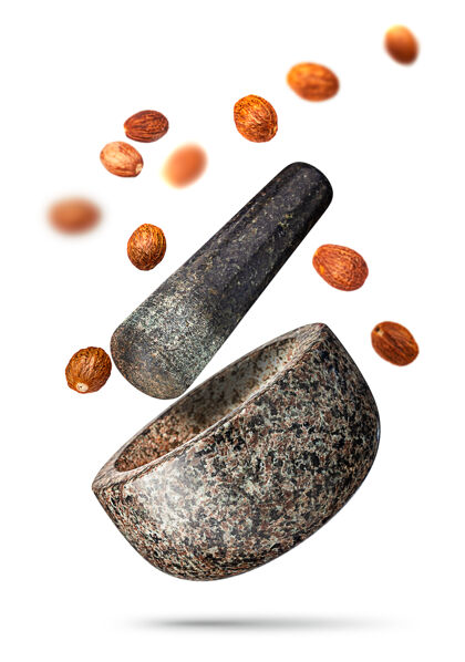 棕色花岗岩砂浆和麝香果仁落在白色背景上孤立研磨机工具碗