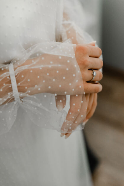 水平戴着灰色围巾的手指上优雅钻戒的特写镜头新娘西装珠宝