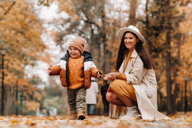 快乐母子俩在秋天散步停车场金秋时节 一家人走过自然公园户外童年户外