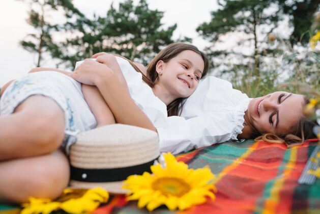 姿势俯视图：快乐的女人微笑着和她可爱的孩子玩耍 躺在户外可爱衣服空气