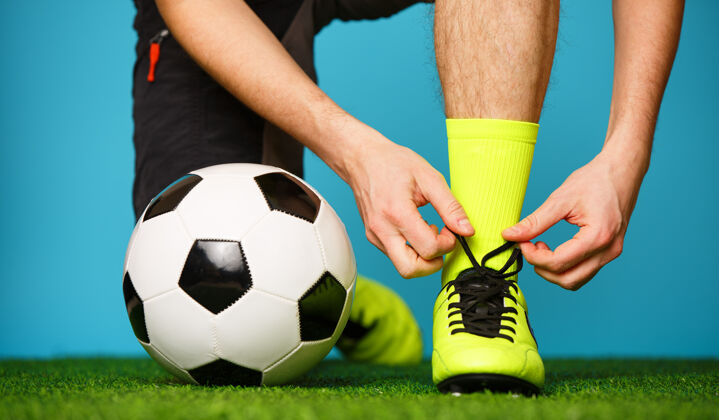 制服准备比赛的足球运动员正在系鞋带运动胜利足球