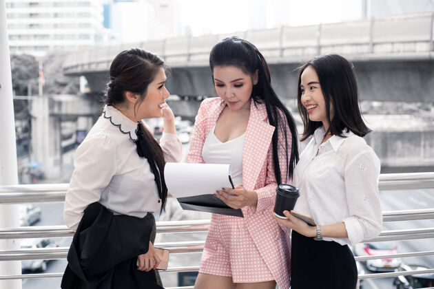 炎症一群亚洲女商人在户外微笑着看工作手册上的信息城市概念亚洲团队精神女士.泰语女上班族女孩女性追随者