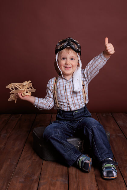 飞机戴头盔的小男孩和木头玩具玩飞机男孩梦想成为一名教师飞行员假期男人们头盔飞机飞行员