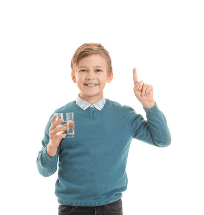 肖像可爱的小男孩拿着一杯水 把食指举在白色的脸上纯净目录孩子