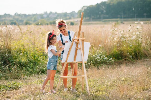 女人家庭 孩子和人的概念-快乐的母亲和女儿在绿色的表面上画画和交谈孩子教学亚洲