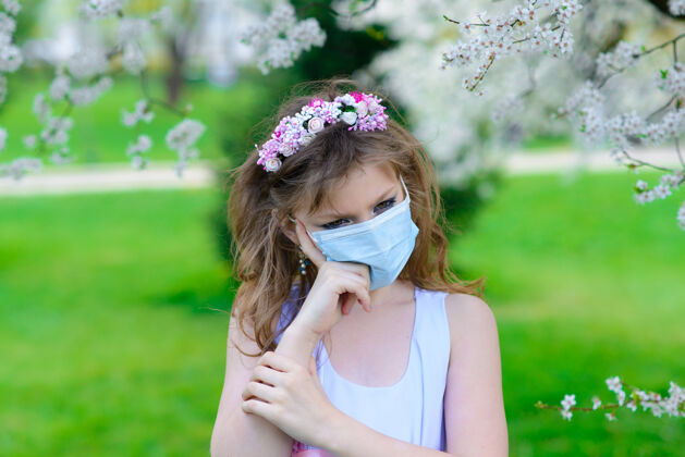 肖像春花里戴着医用口罩的少女花园.概念社会距离 预防冠状病毒户外花园病毒