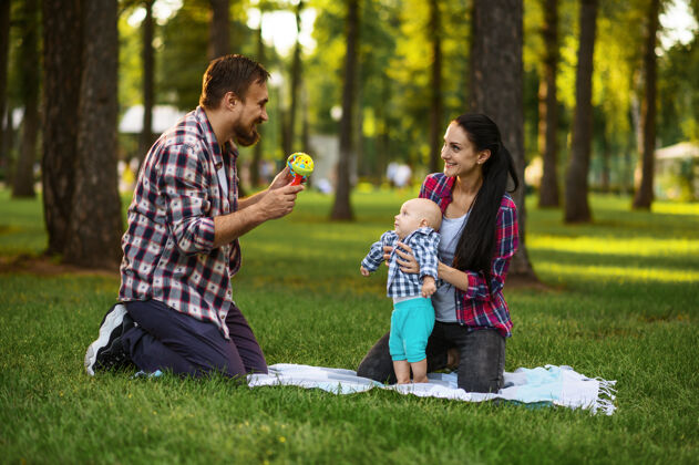 夏天妈妈 爸爸和小宝宝在夏季公园的草地上玩耍乐趣女人小