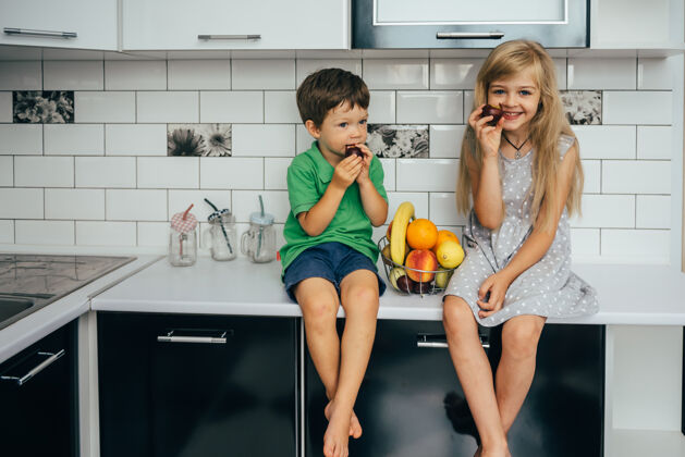女人健康的概念吃有趣孩子们在厨房里吃水果女孩家庭人