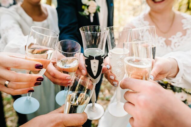 向上干杯新婚夫妇和朋友喝香槟户外人为你庆祝并举杯toast.组男人和女人庆祝婚礼干杯聚会关闭