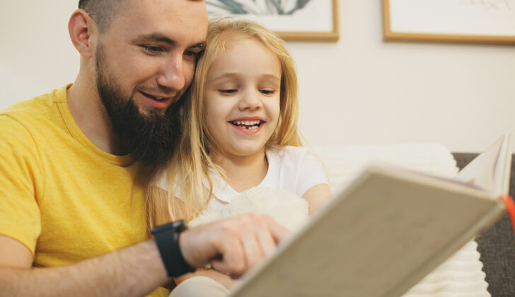 快乐开朗的金发女孩和她留着胡子的父亲一起看书男人休闲父母