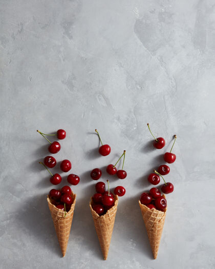 美味健康成熟的红色水果樱桃和华夫饼杯自制冰激凌在灰色石头背景与地方文本.夏季有机吃顶查看有机冰淇淋背景