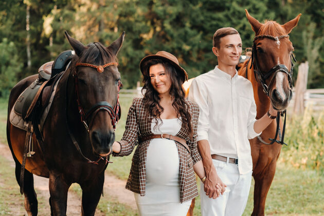 马一个戴着帽子的孕妇和一个穿着白色衣服的男人在大自然中骑马散步妈妈怀孕美女