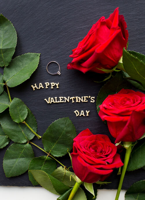 木材黑色表面上有玫瑰的情人节快乐题词特写纹理装饰情人节