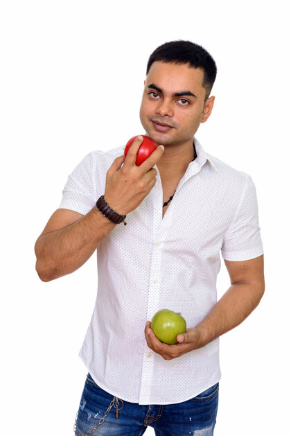 男性年轻英俊的印度男人拿着红绿相间的苹果隔离在白色的空间里饮食20多岁健康