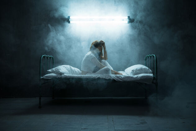 神秘抑郁的精神病女人坐在床上 失眠 黑暗的房间…迷幻的女人每天晚上都有问题 抑郁和压力 悲伤 精神病医院女孩精神病学疯狂