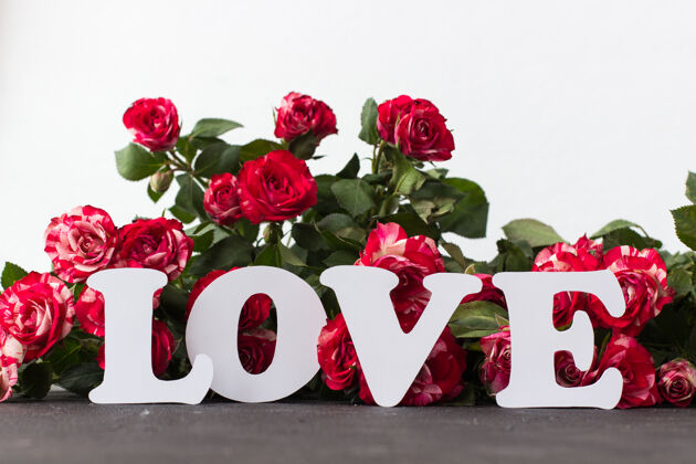 周年纪念在混凝土上红色玫瑰的背景下 白色的题词“爱”混凝土激情新鲜