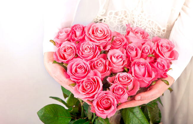 花园一束粉红色的玫瑰在女性手中呈心形周年纪念植物自然