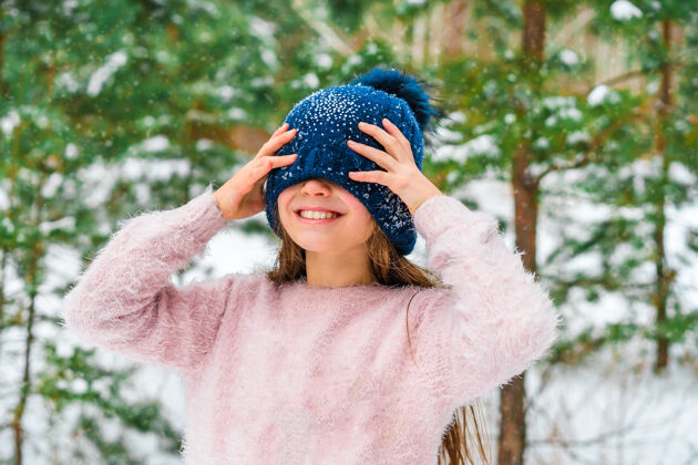 女性一个穿着毛衣戴着帽子的快乐小女孩的冬季肖像 背景是雪景十二月冰霜冻