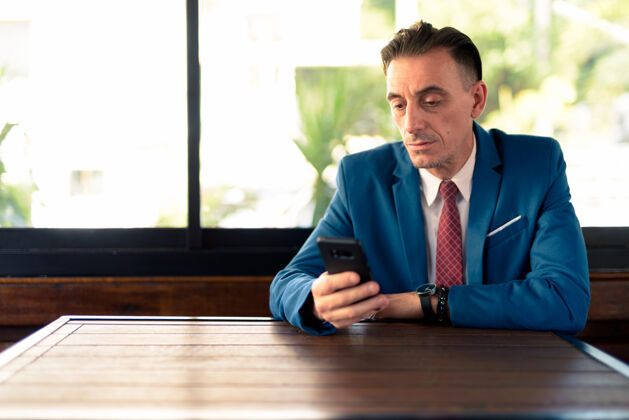 吸引力成熟英俊的意大利商人在咖啡店放松的画像城市科技社交媒体
