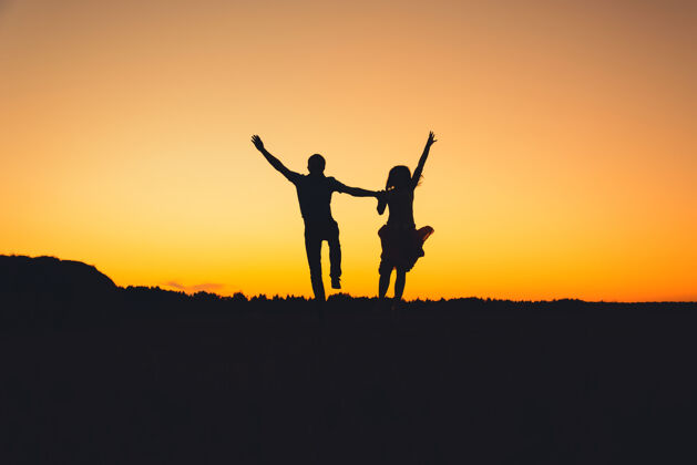 家庭剪影情侣们在夏日的橙色夕阳背景下快乐地跳跃着快乐健康能量