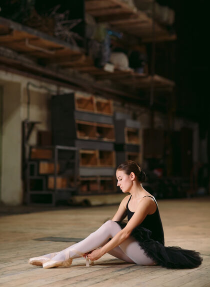 木地板身着黑色礼服的年轻芭蕾舞演员在幕后训练优雅姿势芭蕾舞演员