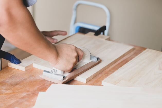 持有木工企业家们正在用砂纸装饰木片 为他们的客户组装木桌圆形工业人