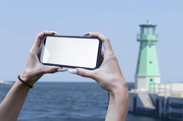 移动女孩手里拿着一个智能手机特写镜头 背景是白色屏幕海.mock-升级技术云空白海滩