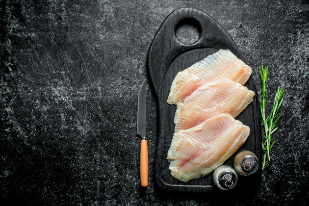 食物用刀 香料和迷迭香把鱼片放在砧板上美味物体肉