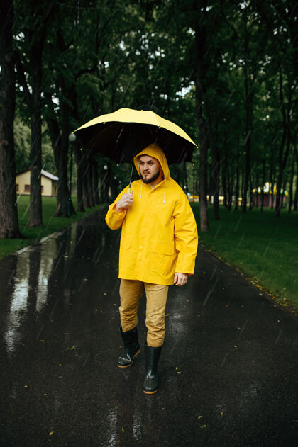 橡胶雨中带伞的人在公园散步白天男性穿着雨衣和胶靴的人 巷子里天气潮湿雨伞白天风景