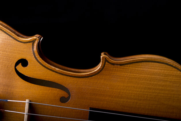演奏管弦乐队的小提琴乐器特写隔离在黑色上旋律经典背景