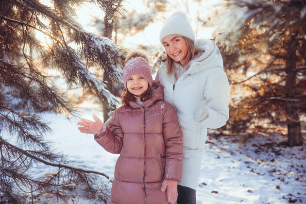 白种人妈妈和女儿在冬季公园玩得很开心寒冷年轻父母