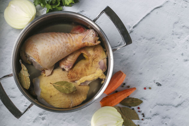 维生素用自制鸡肉和胡椒和月桂叶在大理石背景上的平底锅里煮肉汤胡萝卜顶视图健康