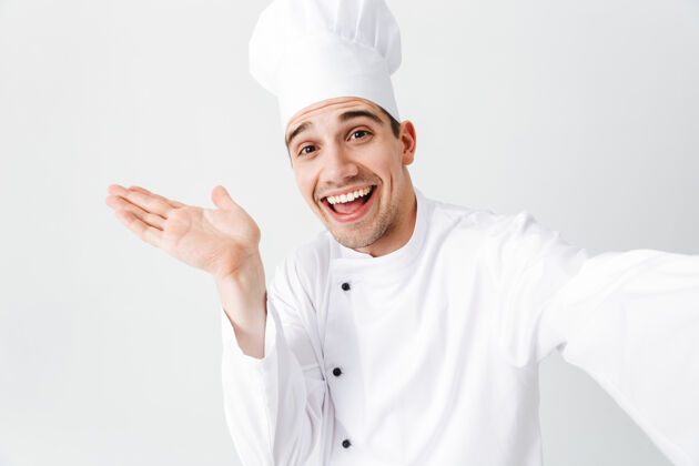 菜肴穿着制服的快乐厨师长孤立地站在白墙上 自拍工人帽子人