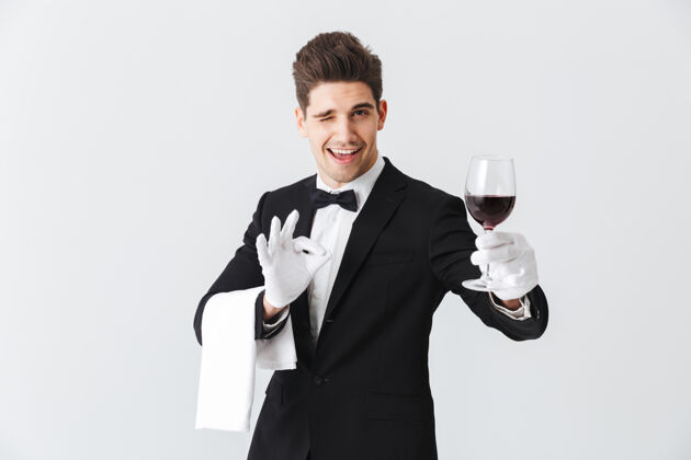白种人年轻帅气的侍者穿着燕尾服 端着一杯红酒隔着灰色的墙女服务员钢铁燕尾服