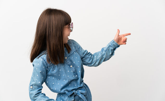 指向戴着太阳镜的小女孩在白色背景下用手指指着侧面展示产品点介绍欢迎