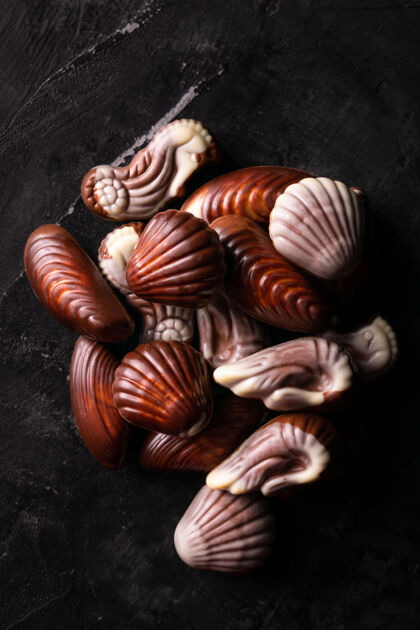 贝壳黑桌子上的比利时巧克力贝壳平躺蜗牛顶视图