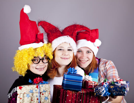 礼物三个戴着滑稽帽子过圣诞节的女朋友礼品工作室射击圣诞老人快乐女孩